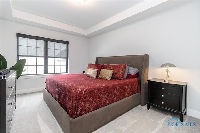 bedroom with carpet floors, a raised ceiling, and baseboards