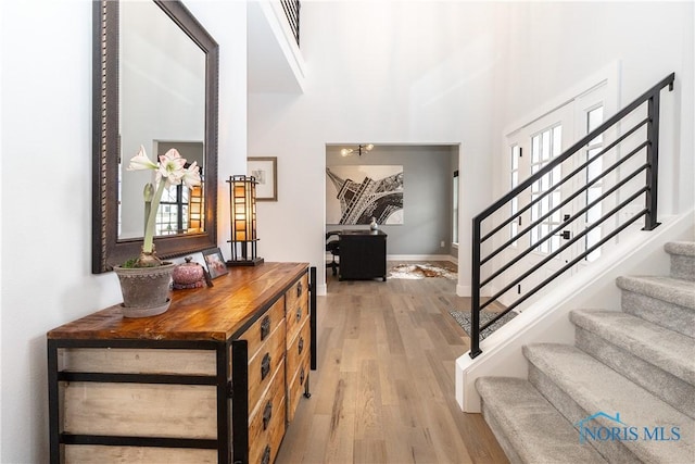 entrance foyer with light wood-style flooring, stairway, and baseboards