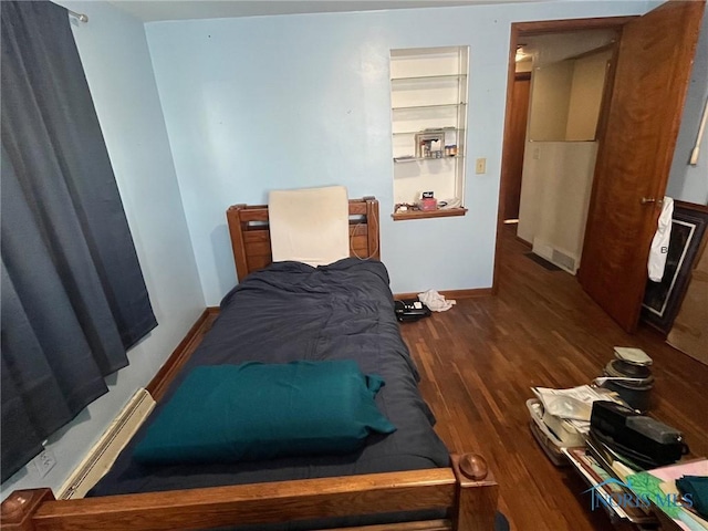 bedroom with a baseboard radiator, wood finished floors, and baseboards