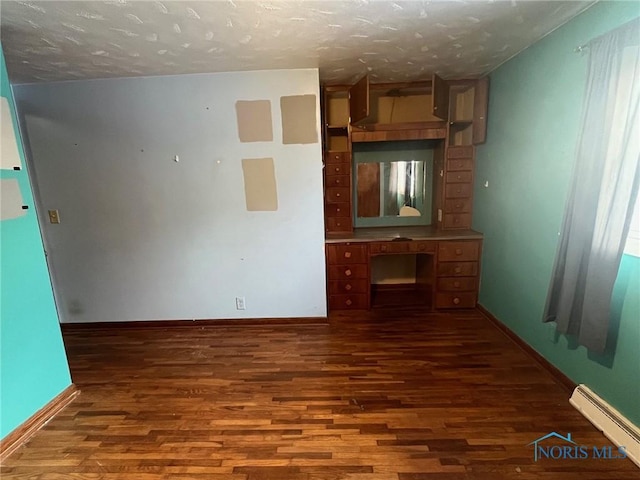 spare room featuring a textured ceiling, a baseboard radiator, and wood finished floors