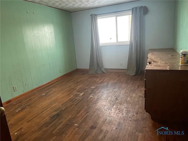 unfurnished bedroom featuring hardwood / wood-style flooring and wood walls