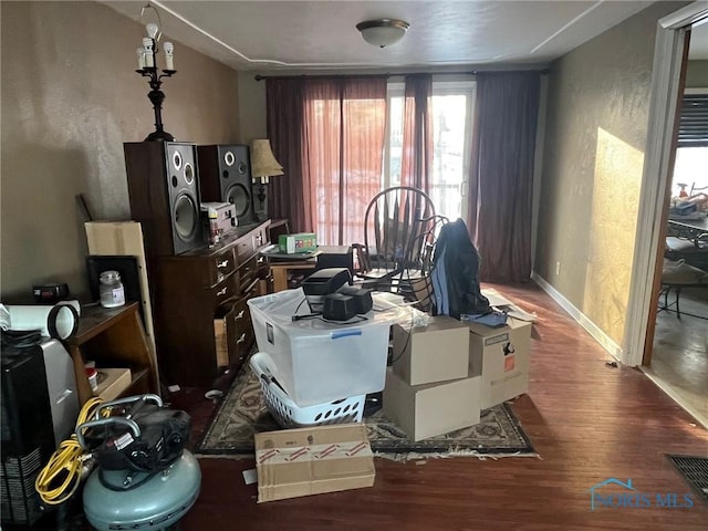 miscellaneous room featuring a textured wall, wood finished floors, visible vents, and baseboards