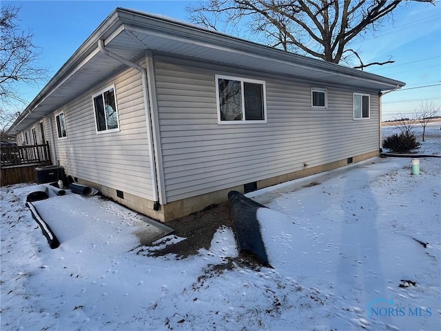 view of snowy exterior with a garage and crawl space