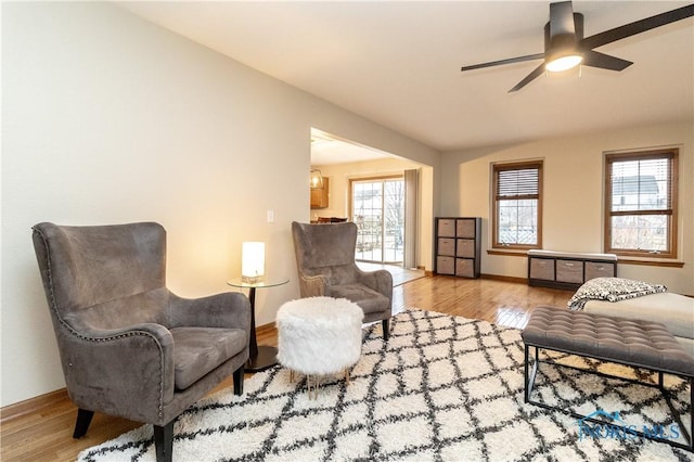 living area featuring baseboards, wood finished floors, and a ceiling fan