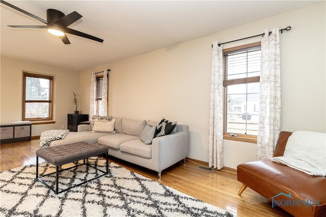 living area with baseboards, a healthy amount of sunlight, wood finished floors, and a ceiling fan