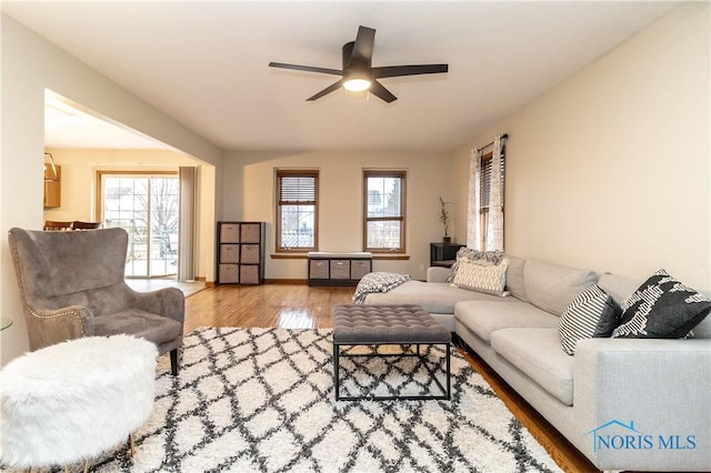 living area with ceiling fan, baseboards, and wood finished floors