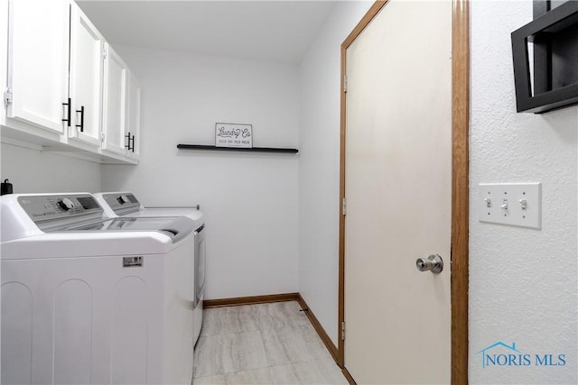 washroom with baseboards, cabinet space, and washing machine and clothes dryer