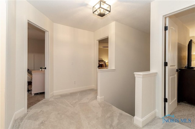 hall with baseboards, an upstairs landing, and carpet flooring