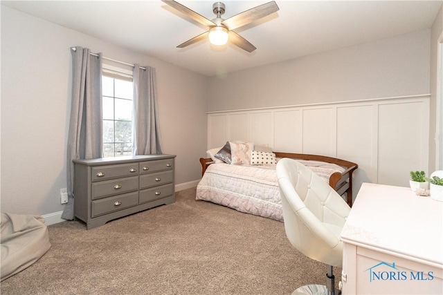 bedroom with a decorative wall, ceiling fan, carpet, and a wainscoted wall