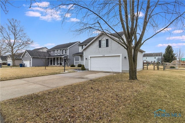 traditional-style home featuring concrete driveway, a front lawn, fence, and a residential view