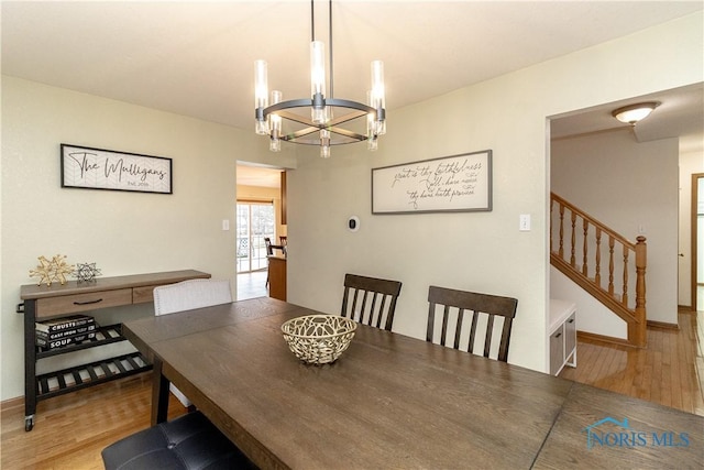 dining room featuring a chandelier, stairs, baseboards, and wood finished floors