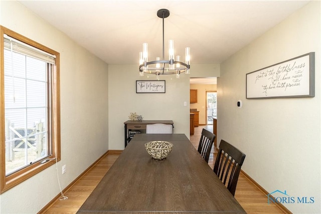dining room featuring light wood finished floors, a chandelier, and baseboards