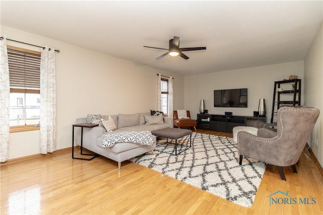 living area featuring ceiling fan, baseboards, and wood finished floors