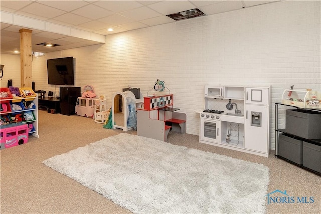 recreation room featuring carpet flooring and a paneled ceiling