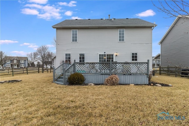 rear view of property with a deck, a lawn, and fence