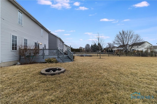 view of yard with a fire pit, a deck, and fence