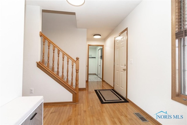 entryway featuring stairs, baseboards, visible vents, and light wood finished floors