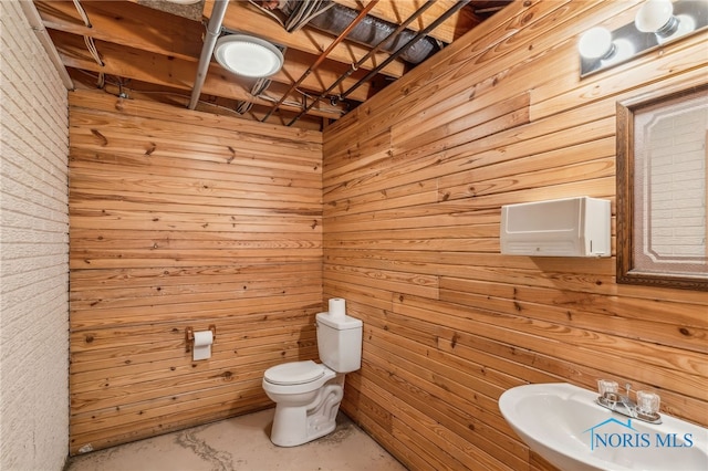 bathroom with toilet, concrete flooring, and a sink