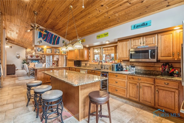 kitchen with stainless steel microwave, wooden ceiling, a sink, beverage cooler, and a kitchen breakfast bar