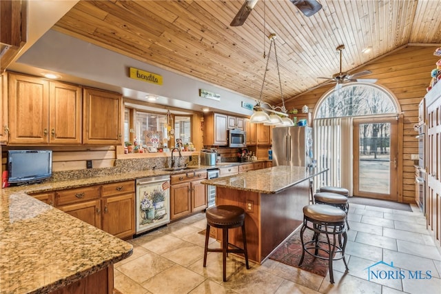 kitchen featuring a sink, a ceiling fan, a kitchen breakfast bar, appliances with stainless steel finishes, and light stone countertops