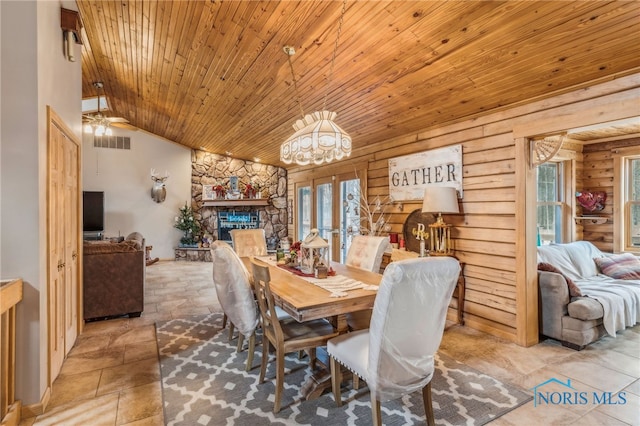 dining room featuring visible vents, stone finish floor, wood ceiling, vaulted ceiling, and a stone fireplace