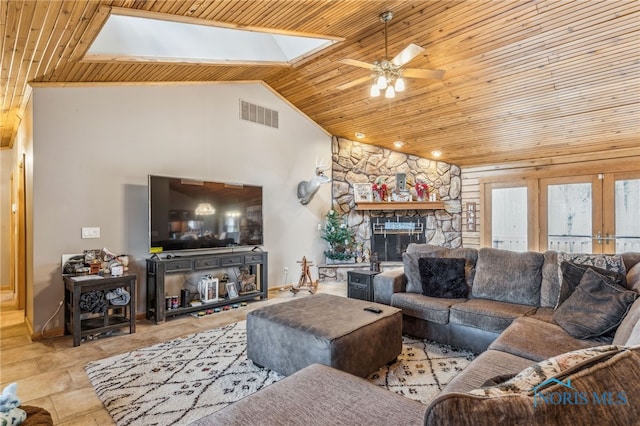 living area featuring a skylight, wood ceiling, visible vents, and a stone fireplace