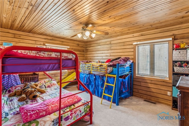 bedroom with ceiling fan, wooden walls, carpet flooring, wood ceiling, and visible vents