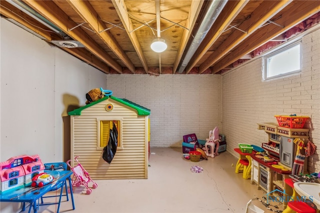 recreation room with brick wall and concrete floors