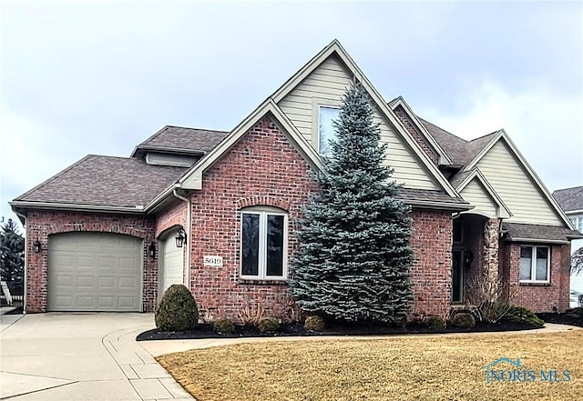 view of front of home with a front lawn, concrete driveway, brick siding, and an attached garage