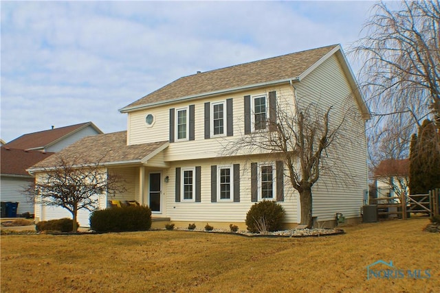 colonial home featuring a garage, roof with shingles, and a front lawn