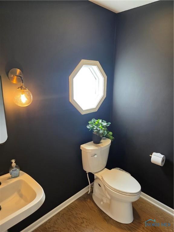 bathroom featuring toilet, baseboards, a sink, and wood finished floors