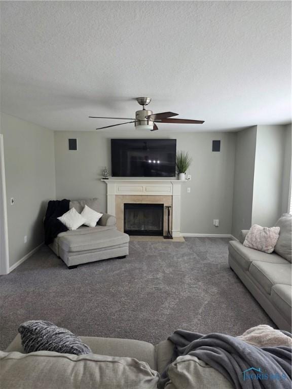 living area featuring a fireplace with flush hearth, carpet flooring, ceiling fan, a textured ceiling, and baseboards