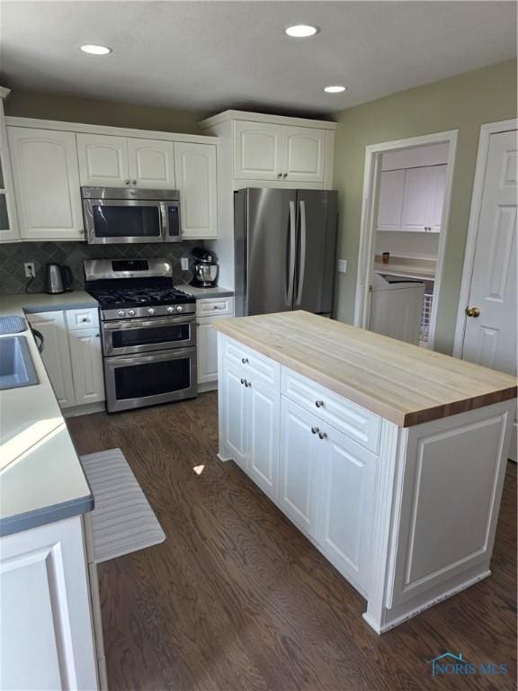 kitchen featuring dark wood-style flooring, wood counters, a kitchen island, white cabinetry, and appliances with stainless steel finishes