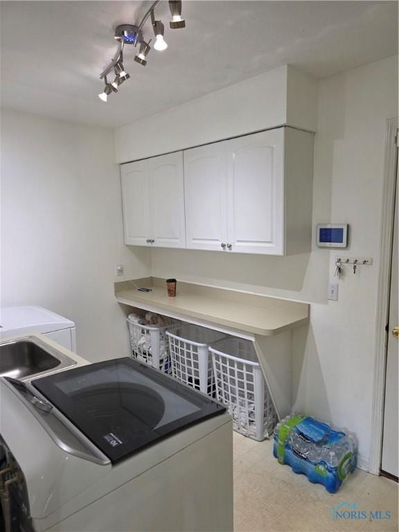 laundry room featuring washer and dryer, cabinet space, and track lighting