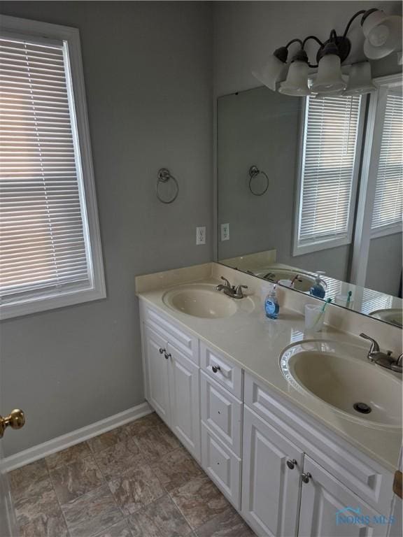 full bath featuring double vanity, a sink, and baseboards