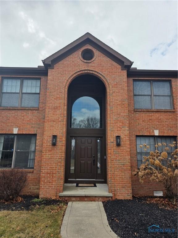 doorway to property featuring brick siding