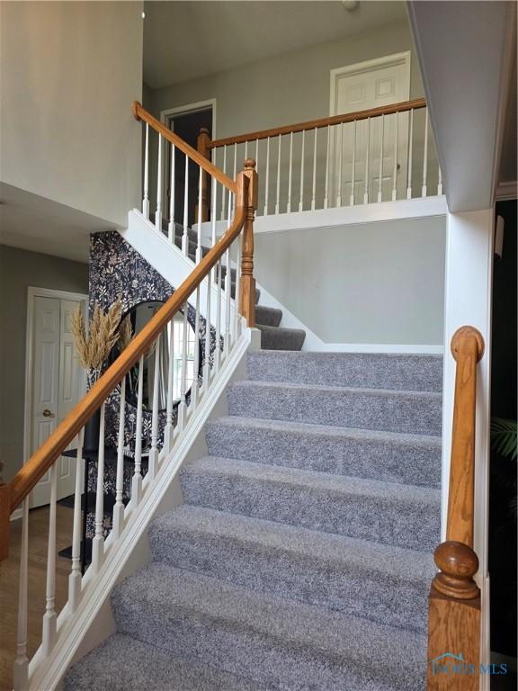 staircase with a high ceiling and wood finished floors