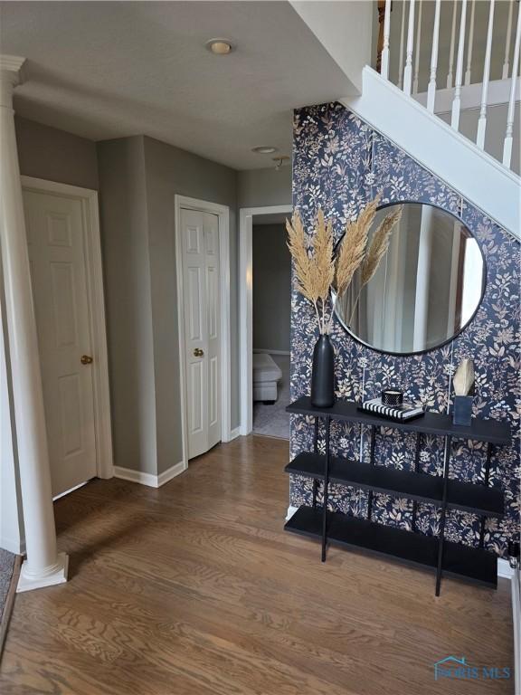 interior space featuring decorative columns, baseboards, and wood finished floors