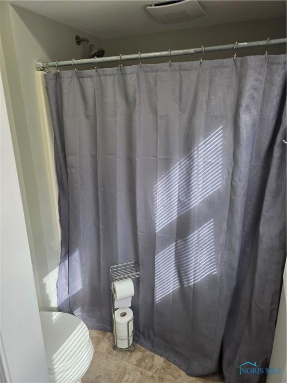 full bath with a shower with curtain and visible vents