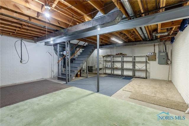 unfinished basement featuring electric panel, brick wall, and stairs