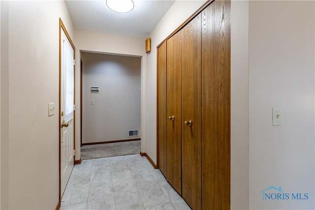 hall featuring a textured ceiling and baseboards