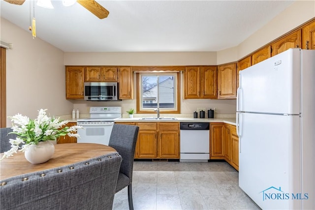 kitchen with white appliances, brown cabinetry, and a sink