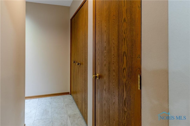 hall featuring baseboards and light tile patterned floors