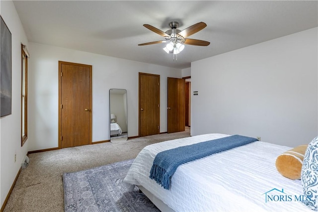 carpeted bedroom featuring a ceiling fan, baseboards, and two closets