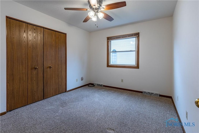 unfurnished bedroom featuring ceiling fan, visible vents, baseboards, a closet, and carpet