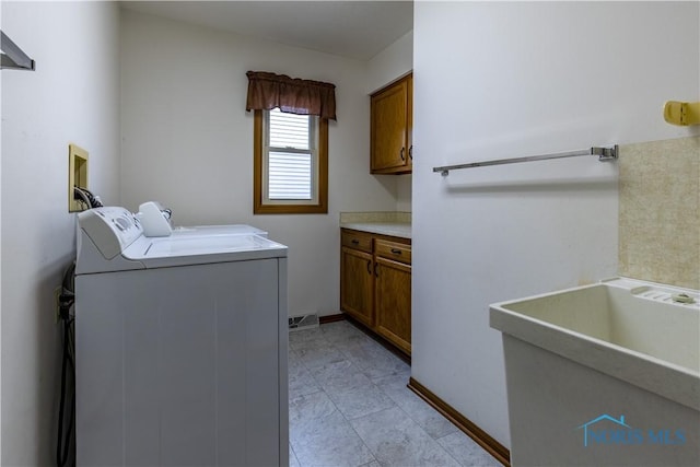 washroom featuring cabinet space, baseboards, and washer and dryer