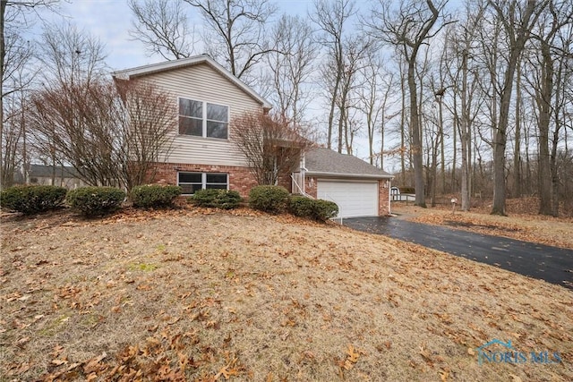 view of front facade with aphalt driveway, brick siding, and a garage