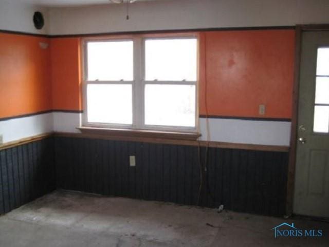 empty room with wainscoting and wooden walls