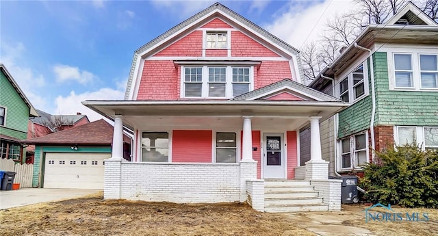 view of front facade with a garage, covered porch, concrete driveway, and a gambrel roof