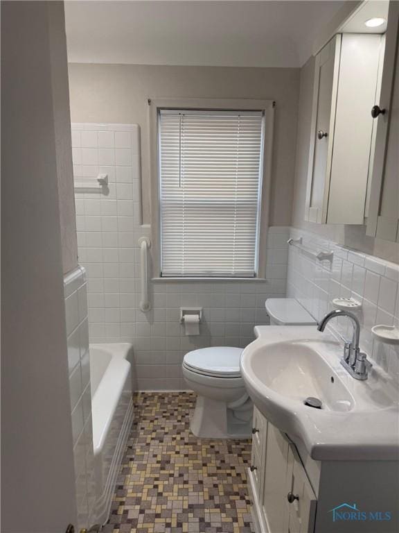 full bath with a bathtub, tile walls, toilet, and vanity